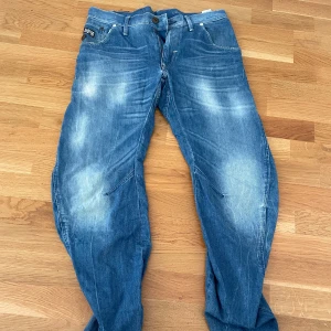 Blå jeans från G-Star RAW - Säljer ett par blå jeans från G-Star RAW med snyggt slitna detaljer och markerade sömmar. 
