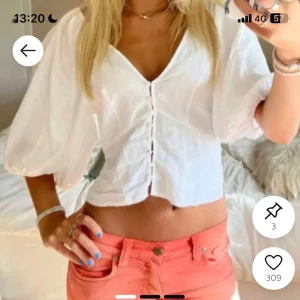 Vit croppad blus med puffärmar - Säljer en söt vit croppad blus med v-ringning och puffiga korta ärmar. Blusen har knappar framtill och en lätt volang vid nederkanten. Perfekt för varma dagar och enkel att matcha med jeans eller kjol.