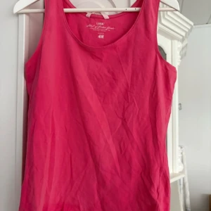 Rosa linnetopp från H&M L.O.G.G. - Säljer en enkel och snygg rosa linnetopp från H&M:s L.O.G.G.-kollektion. Toppen har rund halsringning och är ärmlös, perfekt för varma dagar eller som lager under en tröja. Använd 