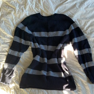 Mörkblå och ljusblå randig stickad tröja från 157 - Säljer en stickad tröja från 157 i mörkblått med breda ljusblåa ränder. Tröjan har lång ärm, rund halsringning och är mjuk och skön. Perfekt för kyligare dagar och enkel att styla med jeans eller kjol.