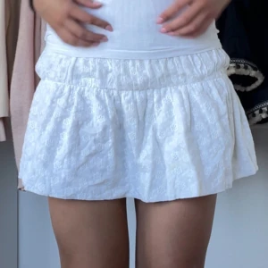Vit mönstrad kjol - Supersöt vit kortkjol med ”spetsblom” mönster över hela kjolen, jätte skönt och den glider inte upp när man går! Som ny, inga defekter!🤍