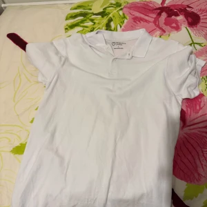 Vit piké t-shirt med krage - En klassisk vit piké t-shirt från primark med krage och korta ärmar. Perfekt för en clean och enkel stil. T-shirten har knappar vid halsen och är tillverkad i mjuk bomull.