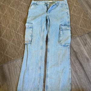 Ljusblå cargobyxor från Perfect Jeans - Säljer ett par ljusblå cargobyxor från Gina tricot med raka ben och stora fickor på sidorna. Byxorna har normal passform, dragkedja och knapp i midjan. Perfekta för en avslappnad stil.