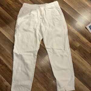 Vita linnebyxor  - Säljer ett par vita linnebyxor från Zara med avslappnad passform och resår i midjan med snörning. Byxorna har två fickor fram och två bakfickor. Perfekta för varma dagar och en stilren look. Det är storlek L men dom har krympt lite i tvätten så dom sitter mer som en M. Vid fler frågor eller funderingar är det bara att höra av sig.