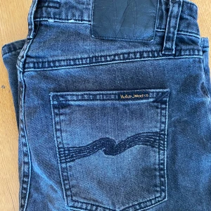 Nudie Jeans - Säljer ett par klassiska  jeans från Nudie Jeans Co med snygga detaljer på bakfickan och logotyp på knappen. Jeansen har normal passform och är tillverkade i slitstarkt denim. Perfekta för dig som gillar stilrena och tidlösa jeans. Skriv vid minsta fundering 