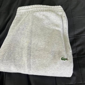 Grå mjukisbyxor från Lacoste - Säljer ett par grå mjukisbyxor från Lacoste med klassisk krokodillogga på benet. Perfekta för en avslappnad stil och riktigt sköna att ha på sig. Använda väldigt lite och i fint skick. Hör gärna av er om ni har några frågor!🙌🙌