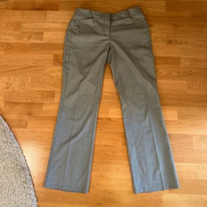 Grå kostymbyxor med rutig mönster - Snygga grå kostymbyxor med diskret rutig mönster. Byxorna har normal passform och raka ben med klassisk look. Perfekta för en stilren och dressad outfit.