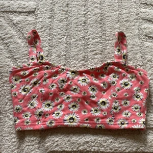 Rosa blommig linnetopp från Tally Weijl - Supersöt rosa linnetopp med vita och gula prästkragar som mönster. Toppen har breda axelband och är perfekt för varma dagar. Mjuk och skön bomullskänsla.