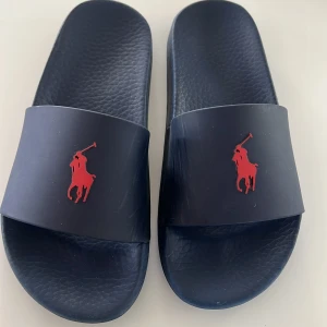 Ralph lauren tofflor - Jag säljer ett par mörkblåa tofflor från Ralph Lauren. De her ett ganska stort rött märke fram till. De är i storleken 40. Nypris: 900 kr och mitt pris är: 350 kr. Skriv bara om ni har någon fråga!