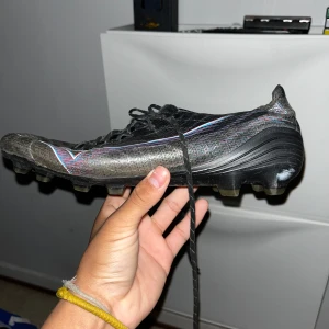 Svarta fotbollsskor från Mizuno - Säljer ett par svarta Mizuno fotbollsskor. Skorna har snörning och platt sula med fasta dobbar för bra grepp på planen. Perfekta för dig som vill sticka ut på fotbollsplanen kanske inte sån här fin skick men funkar o spela i håller väldigt bra och har en kolfiber plattta i skorna. De bara skriva om ni vill se bilder på den  