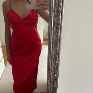 Röd långklänning från Zara - Säljer en röd långklänning från Zara med smala axelband och v-ringad hals. Klänningen har en figurnära passform och är tillverkad i ett glansigt material. Pris kan diskuteras 