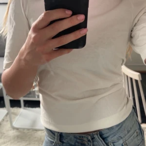 Vit t-shirt från Kappahl - Säljer en vit t-shirt från Kappahl i mjuk bomull. har korta ärmar med liten skrunch detalj. Perfekt basplagg till garderoben och passar till det mesta.