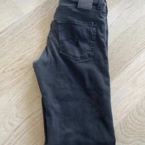 Replay Anbass Hyperflex X-Lite jeans i svart -    Storlek 158cm/13-14 år A14 nypris 1599kr  Säljer ett par svarta Replay Anbass Hyperflex X-Lite jeans. Byxorna har en slim passform och klassisk femficksdesign. Materialet är stretchigt och bekvämt, perfekt för dig som gillar jeans med mycket rörelsefrihet.