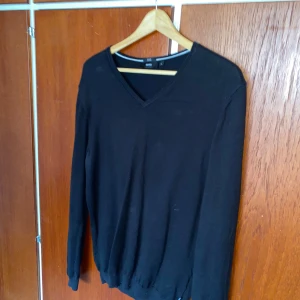 Svart v-ringad tröja från Hugo Boss - En stilren svart tröja från Hugo Boss med v-ringad hals och långa ärmar. Perfekt med skjorta under och passar till många olika outfits. Passar super till sommarkvällar! Pris kan diskuteras vid snabb affär