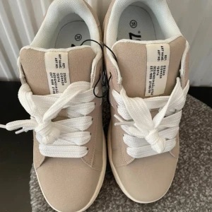 Beige sneakers  - Chunky sneaker i mockaimitation. Rundad tå och lågt skaft. Breda snören Vadderad innersula  Modell Connor från Lager 157 St 38  Nya och oanvända!  Liten fläck på sidan som var vid leverans