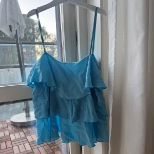 Blå volangtop från French Connection - Jättefin blå topp från French Connection. Färgen syns bättre på den andra bilden! Den har två fläckar som inte är så märkbara men som jag inte lyckats få bort (kanske går med vanish?) och därav nedsatt pris.  Står ingen storlek men skulle uppskatta xs  Prisförslag välkomna! 🥂