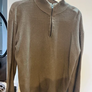 Brun stickad half zip-tröja LMTD - Säljer en brun stickad tröja från LMTD i storlek M. Tröjan har en snygg half zip-dragkedja och ribbad krage. Den är långärmad och har en strukturerad, lite grovstickad yta som ger en cool och avslappnad vibe.
