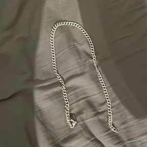 Silverfärgad kedjehalsband - Säljer ett chunky halsband i silverfärg med klassisk kedjelänk. Halsbandet har en stilren och tidlös design som passar perfekt till streetwear eller för att lyfta din outfit. Länkarna är platta och breda vilket ger ett coolt och trendigt intryck.