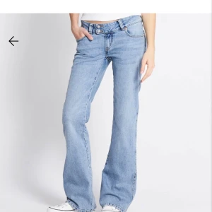 Ljusblå bootcut jeans med broderi - Snygga ljusblå jeans med bootcut passform och låg midja. Jeansen har dubbla knappar i midjan och coolt broderi på bakfickorna. Perfekta för dig som gillar en avslappnad men trendig look.