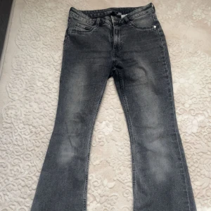 Grå bootcut jeans - Snygga grå jeans med bootcut-modell. Klassisk femficksdesign och normal passform. Perfekta till sneakers eller boots för en avslappnad look. Jeansen är högmidja.