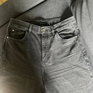 Svarta jeans från Massimo Dutti - Snygga svarta jeans från Massimo Dutti i klassisk femficksmodell. Jeansen har hög midja, raka ben och är tillverkade i bomull med en lätt tvättad finish. Perfekta för dig som gillar en stilren och tidlös look.
