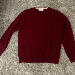 Mörkröd kashmir tröja  - Snygg mörkröd stickad tröja från William Baxter med rund halsringning och långa ärmar. Perfekt för dig som gillar stilrena plagg med enkel design. Tröjan har ribbade muddar vid ärmslut och nederkant för en klassisk look.