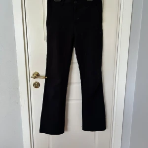 Svarta byxor från XOXO Friends - Svarta byxor från XOXO Friends med klassisk rak passform. Byxorna har normal midja och är tillverkade i ett mjukt material som känns bekvämt hela dagen. Perfekta för dig som gillar en stilren och enkel look, nästan lite som kostymbyxor 