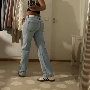 Ljusblå raka jeans med låg midja - Säljer ett par ljusblå jeans med klassisk femficksdesign och låg midja. Jeansen har raka ben och en chill passform som sitter snyggt över höften. Perfekta till sneakers och crop tops för en laidback vibe. Materialet är klassiskt denim i bomull.