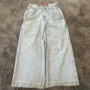 Wide ljusblå jeans från One Eleven - Säljer ett par riktigt feta ljusblå jeans från One Eleven Fat Boy med bred passform och råa kanter nertill. Jeansen har stor bakficka med broderad figur och orange detalj, samt klassiska fem fickor. Perfekta för dig som gillar baggy och streetwear.