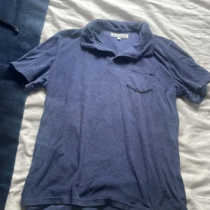 Blå frotté t-shirt från Studios - Blå t-shirt från Studios i frottématerial med korta ärmar och klassisk krage. Har en liten bröstficka som ger en chill vibe. Perfekt för dig som gillar mjuka och bekväma plagg med lite retro känsla.