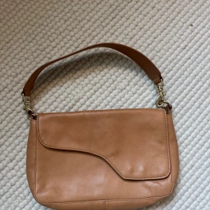 Beige ATP väska i skinn.  - Säljer en stilren beige axelväska i skinn med snyggt formad lock och bred axelrem. Köpt på sample sale. 