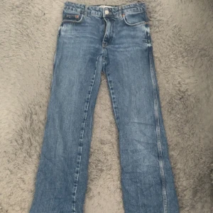 Blå bootcut jeans från Zara - Snygga blå jeans från Zara med bootcut passform och råa kanter nertill. Klassisk femficksmodell med normalhög midja och ljus tvätt. Perfekta för dig som gillar en avslappnad men trendig look.