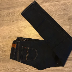 Replay Hyperflex mörkblå jeans - Snygga Replay Hyperflex jeans i mörkblå tvätt med klassiska kontrastsömmar och cool detalj på bakfickan. Modellen har normal passform och är gjorda i stretchigt jeanstyg som sitter skönt hela dagen. Perfekt för dig som gillar stilrena och bekväma jeans.