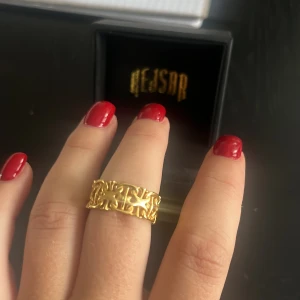 Guldfärgad ring från Kejsar - Säljer en snygg guldfärgad ring från Kejsar med ett unikt, öppet mönster som ger coola vibes. Ringen har en bred design och detaljerade utskärningar som gör den till ett statement piece. Perfekt för dig som gillar att sticka ut med dina accessoarer.