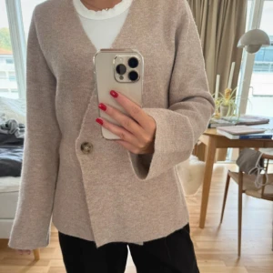 Beige kofta från Neo Noir - Säljer en beige kofta från Neo Noir med v-ringad hals och en stor knapp framtill. 