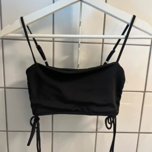 Svart croppad topp - Svart croppad topp, mycket stretchigt och skönt material. Snörningen på sidan gör att man kan välja bredden på toppen. Använd 2-3 gånger