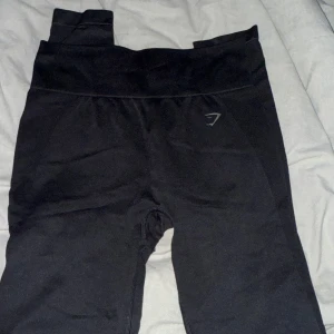 Svarta leggings från Gymshark - Säljer ett par svarta leggings från Gymshark. De har hög midja och är perfekta för träning. Materialet är stretchigt och bekvämt, med Gymshark-loggan synlig på baksidan av midjan. strl. M