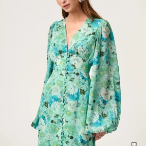 Adoore klänning  - Säljer en vacker mintgrön klänning från Adoore med blommigt mönster. Klänningen har långa ärmar och en v-ringad design med knappar framtill. Aldrig använd.💕Nypris 1695kr.