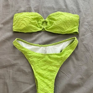 Set Grön bikini  - Trendig grön bikini från SHEIN med en unik textur och bandeau-topp. Toppen har en dekorativ knutdetalj i mitten. Perfekt för sommarens stranddagar!