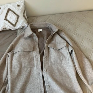 Beige kappa - Säljer en stilren beige kappa. Den har en klassisk krage och knäppning framtill med två stora bröstfickor. Perfekt och  passar till många olika outfits.
