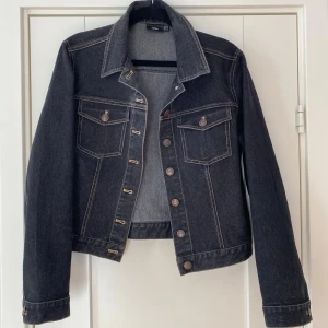 Svart jeansjacka från InWear - Snygg svart jeansjacka från InWear med klassisk krage och knappar framtill. Jackan har två bröstfickor med knappdetaljer och kontrastsömmar som ger en cool look. Perfekt för en avslappnad stil.  Svart jeansjacka i strl 38 från Inwear.  Endast använd vid ett par tillfälle och är i nyskick.  Mått Över bröstet: ca 50 cm Längd från axeln och ner: ca 49 cm  65% bomull, 31% polyester och 4% elastan   Kommer från ett djur och rökfritt hem.