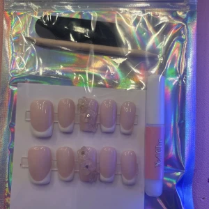 Fransk manikyr - Säljer ett set med fransk manikyr lösnaglar i ljusrosa och vitt. Två av naglarna har extra dekorationer med pärlor och blommor. Perfekt för en elegant look. Setet inkluderar nagelfil, nagelbands prep  och nagellim.❤️