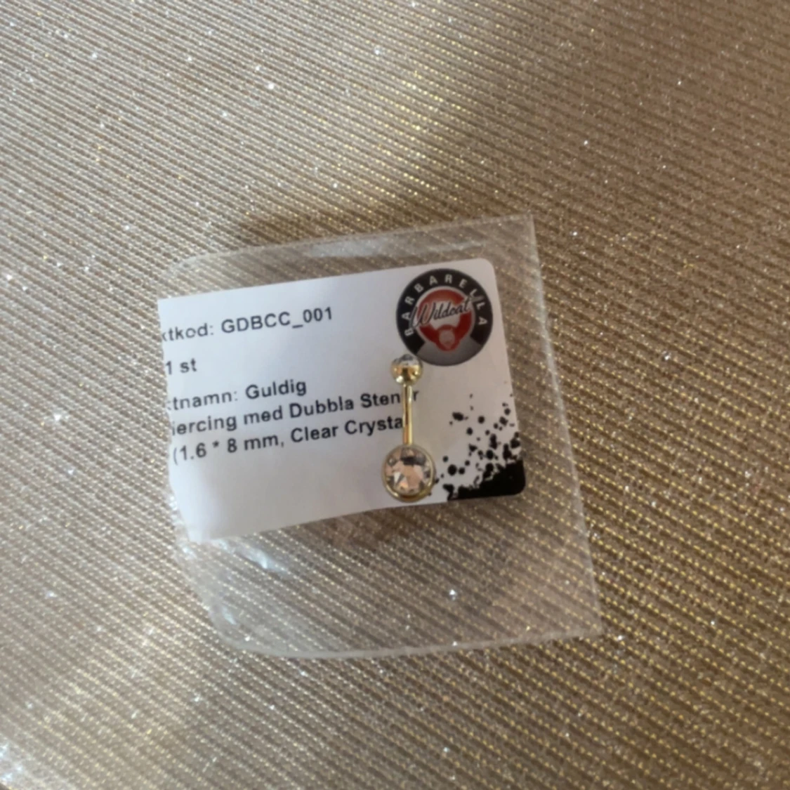 Guldig piercing med dubbla stenar