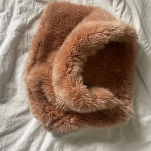 Brun fluffig halsduk från Zara - Säljer en supermjuk och fluffig brun halsduk från Zara. Perfekt för att hålla sig varm och stilren under kyliga dagar. Den har en lyxig känsla och är lätt att matcha med olika outfits. Ett måste för garderoben!