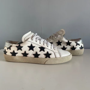 Vita sneakers med stjärnor från Saint Laurent - Riktigt snygga Saint Laurent skor som inte har varit använda så länge. De är i bra skick och för ett rimligt pris! Original pris 7 000kr. Det är i storlek 40 men passar storlek 41! Det kommer inte original box med men de kommer i en box. Skriv gärna om ni har några frågor!