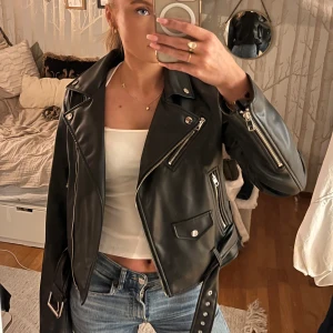 Svart skinnjacka - Snygg svart skinnjacka med dragkedja. Jackan har flera dragkedjor och fickor med bälte i midjan. Perfekt för en cool och edgy look. Från Zara i strl M men passar mer Xs-M💞