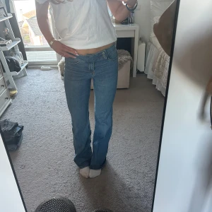 Lågmidjade jeans - Snygga blå jeans från Divided med en klassisk bootcut-stil. De har en normal passform och är perfekta för en avslappnad look. Jeansen en supercool knäppning vilket gör det väldigt unika och är tillverkade i ett bekvämt denimtyg.