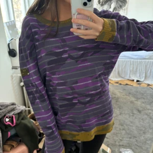 Lila och grön camouflagemönstrad tröja - Säljer en unik lila och grön camouflagemönstrad tröja med långa ärmar. Så varm och cool, använd en gång endast så i fint skick! I ull och köptes för 1000kr