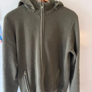 Olivgrön stickad hoodie/ cardigan från Indicode - Hej,  Säljer du nu denna väldigt eftertraktade cardigan/tröja. Slutsåld över allt.  Storlek M i toppskick, har endast använt två gånger.   Hör av er vid fler frågor