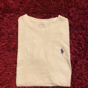 Vit t-shirt från Ralph Lauren - Säljer en klassisk vit t-shirt från Ralph Lauren.            T-shirten är kortärmad och tillverkad i mjuk bomull. Perfekt för en stilren och avslappnad look. Den har två jätte små fläckar i undre delen av tröjan som är på framsidan. Utöver det så är det inga defekter.